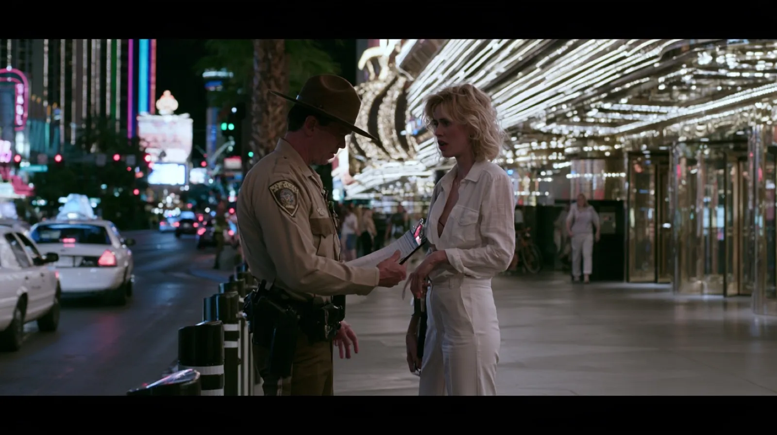 Law enforcement officer speaking with a woman on the Las Vegas Strip during a nighttime vice-related investigation.