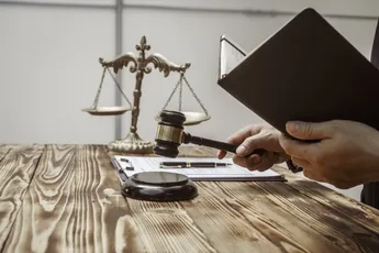 A businessman in a formal suit signs a contract, hands close up, suggesting possible bribery