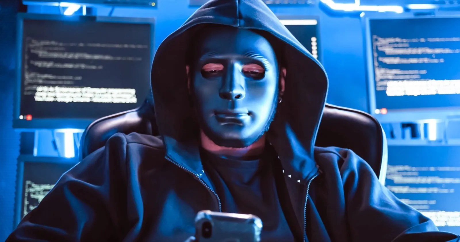 A hacker wearing a mask to cover his face is using computer to hack data to get ransom from victims.