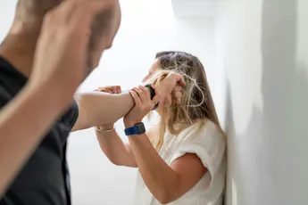 A man mistreating a woman by pulling her hair