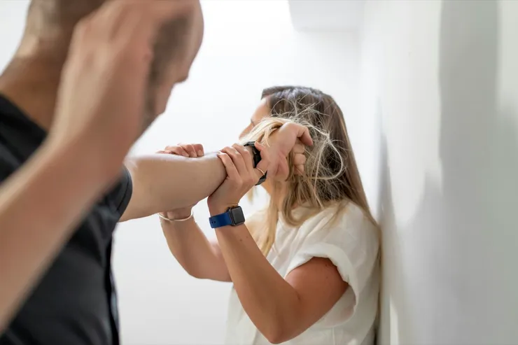 A man mistreating a woman by pulling her hair