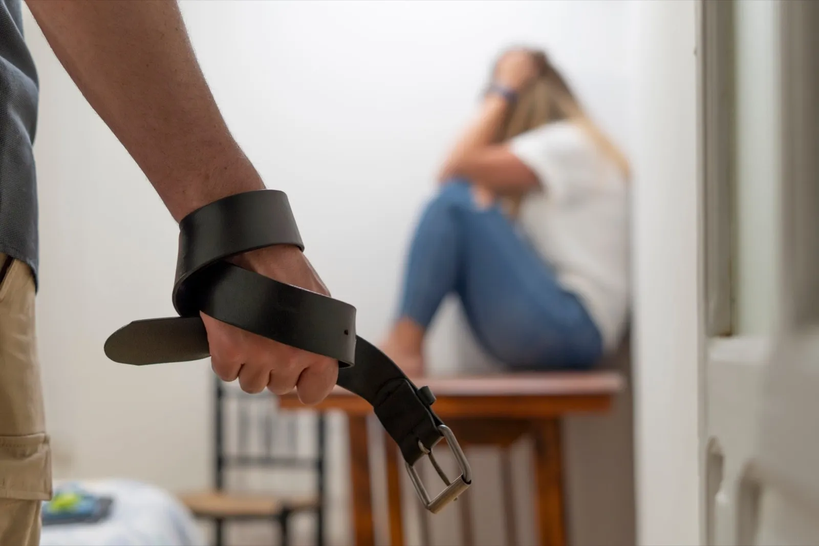 A man mistreating a woman with a belt
