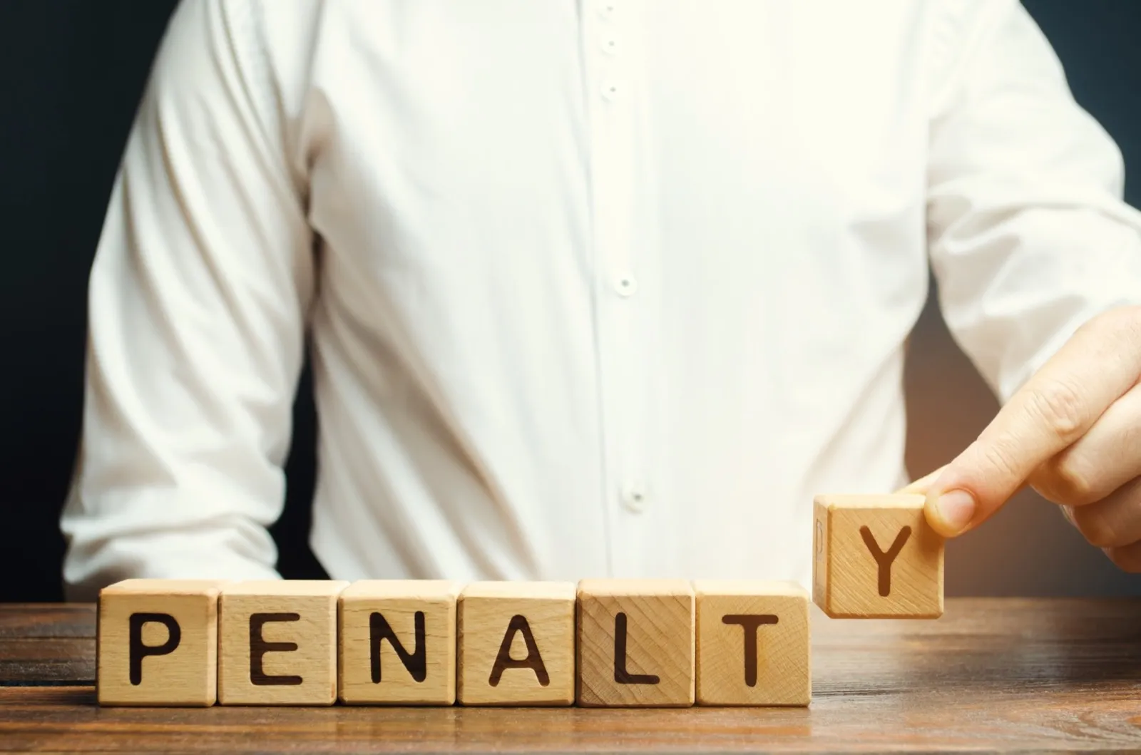 A man puts a wooden blocks with the word Penalty