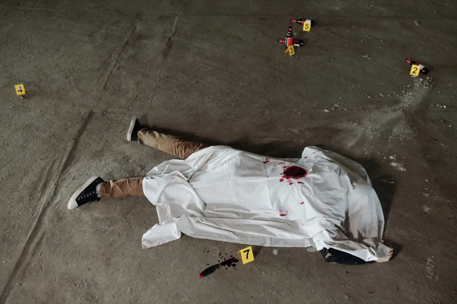 Above shot of dead man covered with white sheet lying on asphalt