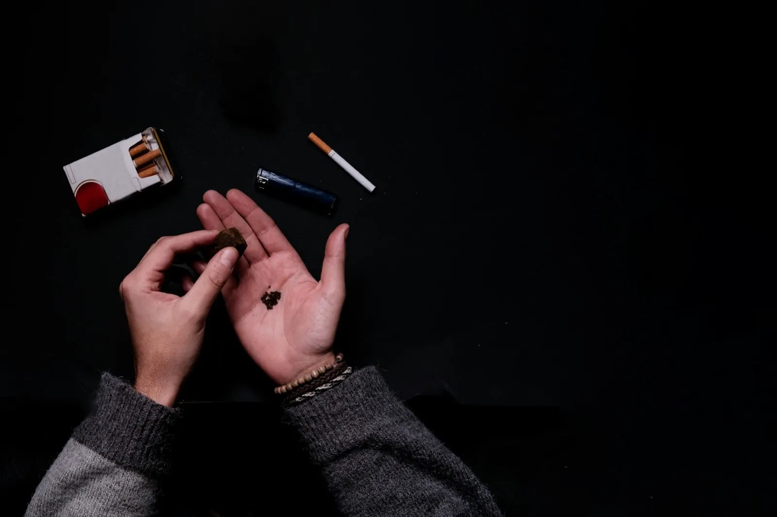 Aerial view of unrecognizable male hand rolling a hash marihuana joint