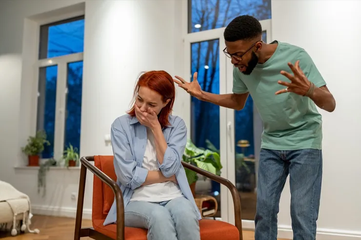 Angry African American man husband abuser yelling at upset crying wife at home