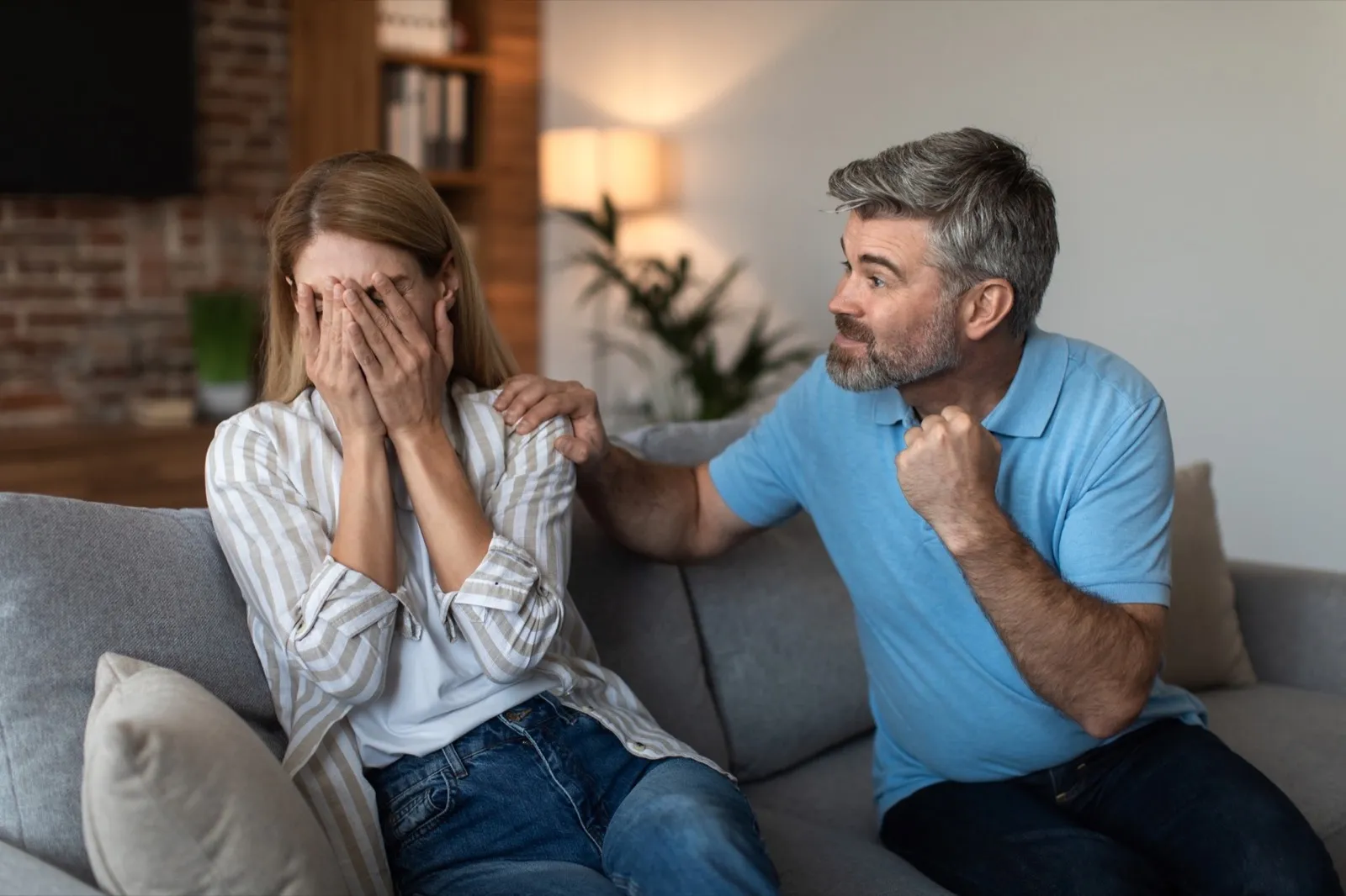Angry aggressive mature caucasian husband with beard threatens to scared wife with fists