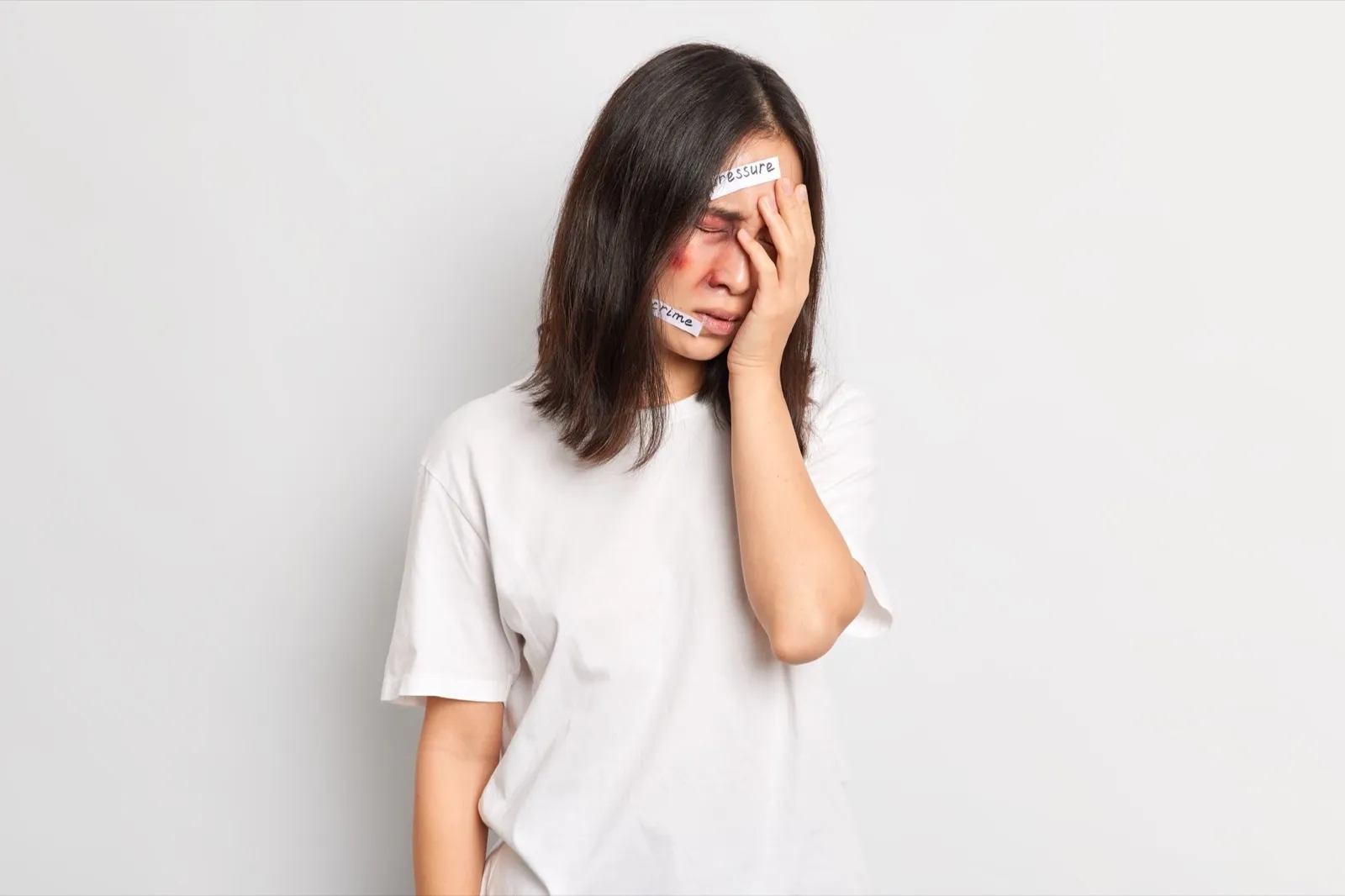 Assaulted displeased Asian woman covers face with hand lives in terror and pressure stands injured h