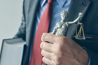 Attorney holding law book and statue of Lady Justice