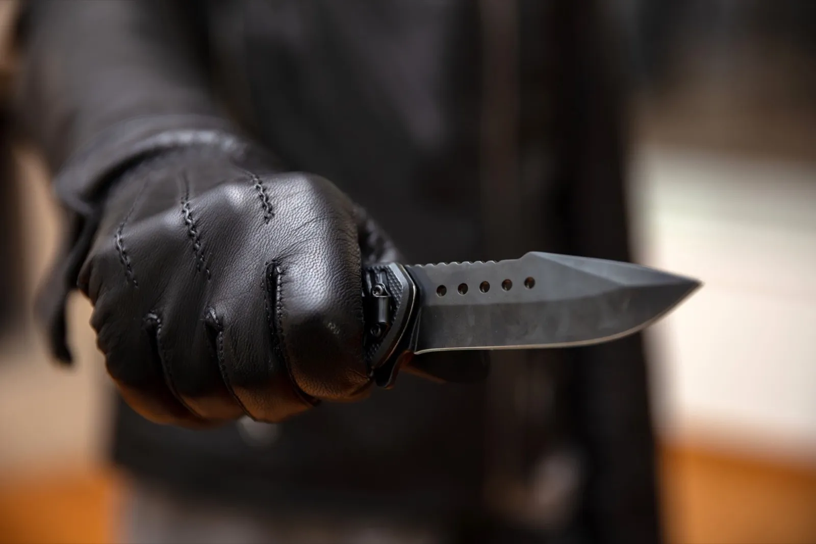 Burglar holding a knife in gloved hand, armed robbery concept.
