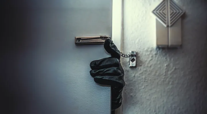 masked burglar with crowbar breaking and entering into a victim's home