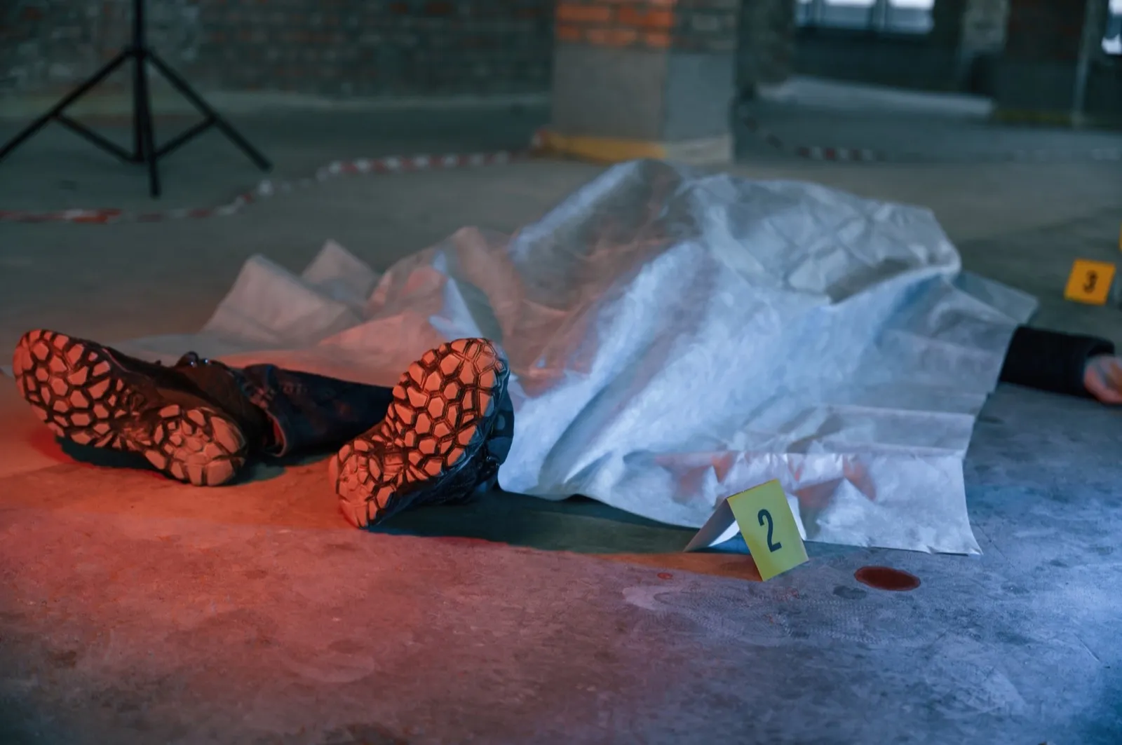 Dead body of a man is on the ground, covered in white cloth. Conception of murder, homicide