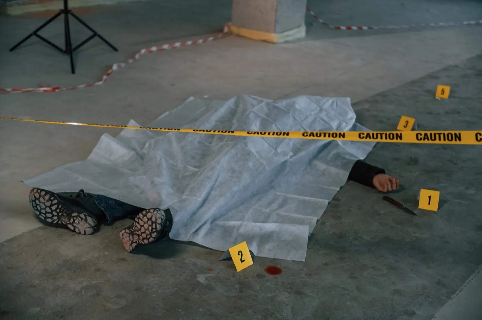 Dead body of a man is on the ground, covered in white cloth. Conception of murder, homicide