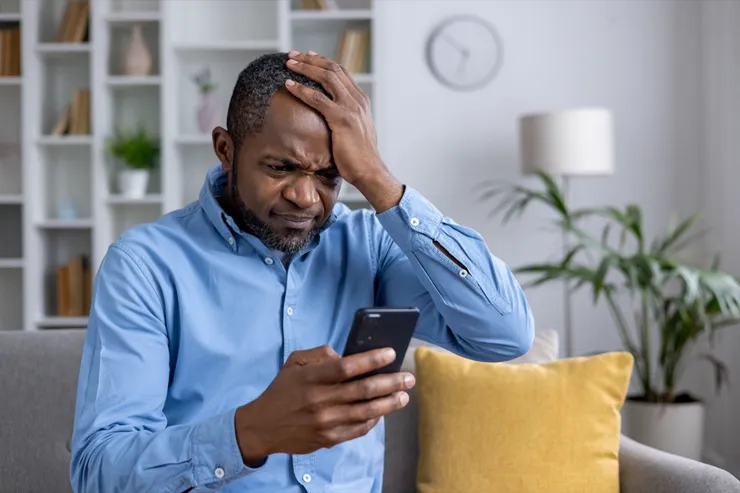 Distressed man discovering fraud on his mobile device