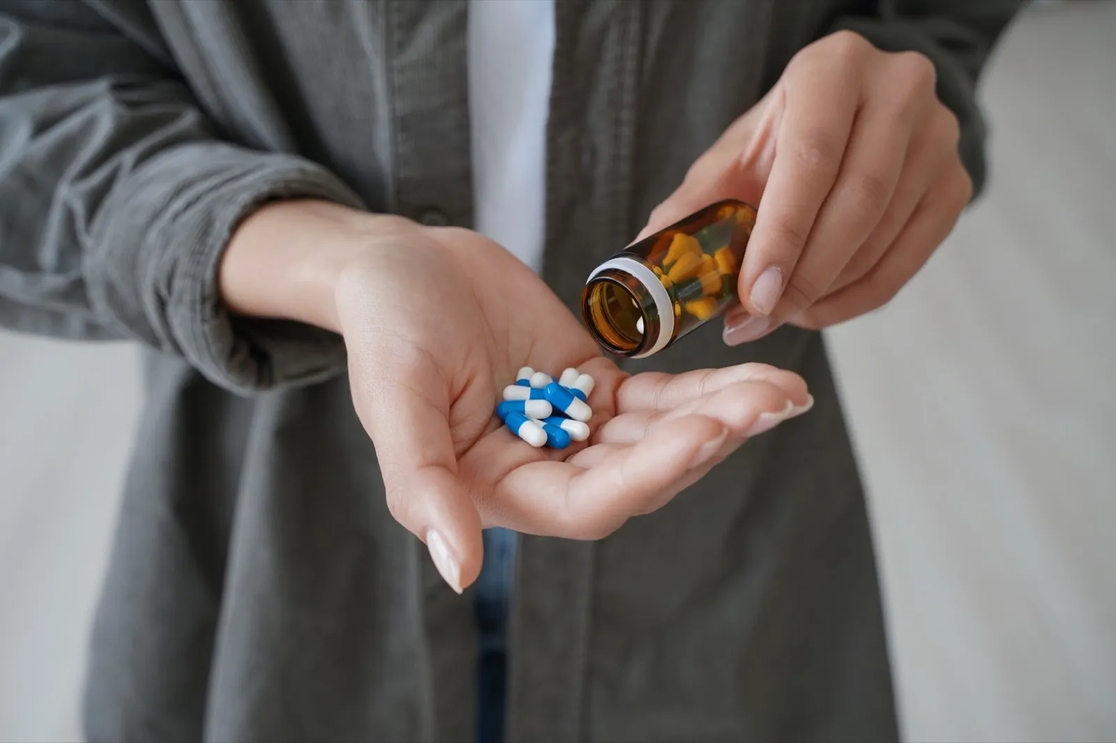Drug addiction. Hand of african american girl or young woman holding medicine drugs and and flacon.