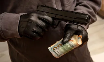 Gloved hand holding a pistol stealing money, closeup view. Armed robbery concept