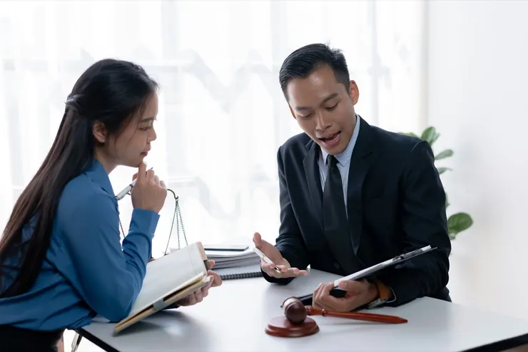 Lawyer and client discussing legal strategy with a gavel and scale of justice in the background.
