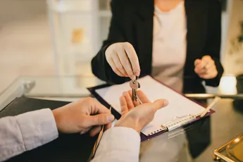 Millennial man receiving keys from real estate agent in the office. Buying a property.