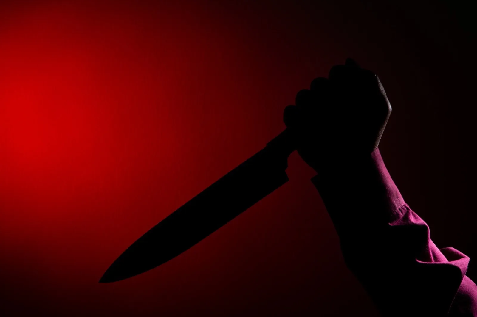 Murderer with big knife in hand of scary crime scene