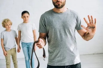 partial view of abusive father with inscription on palm and sad kids