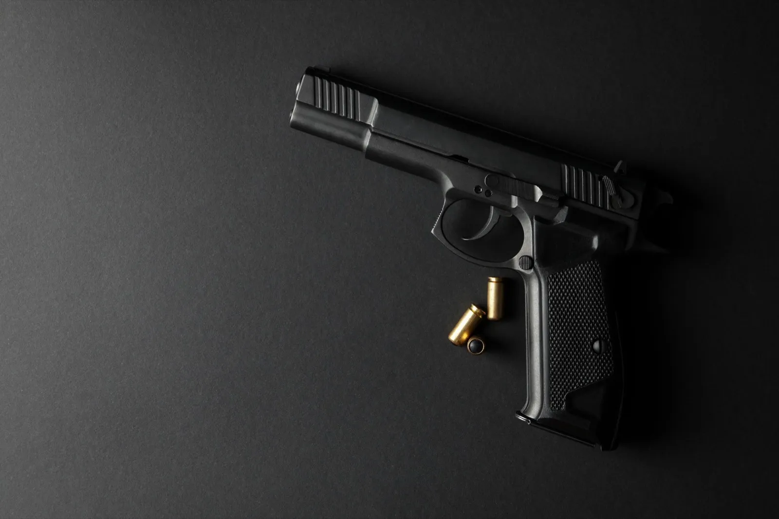 Pistol and traumatic bullets on black background. Self defense weapon
