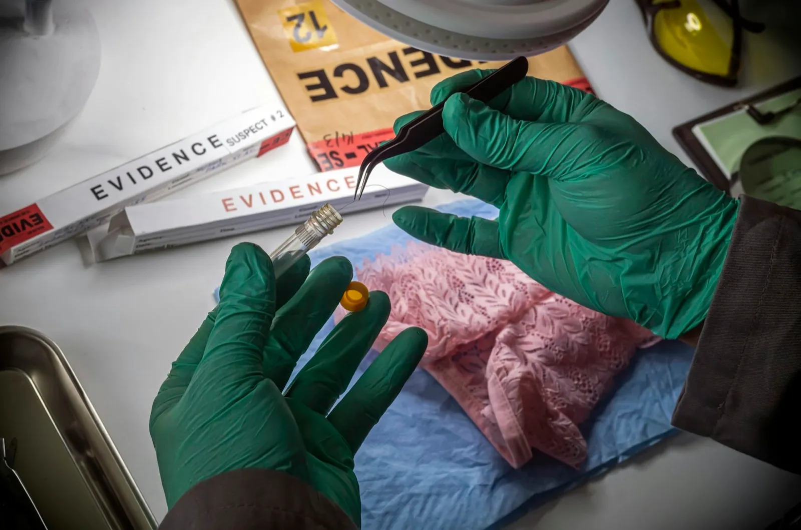 Police scientist inserts rape victim’s hair into vial for crime lab DNA research, conceptual image
