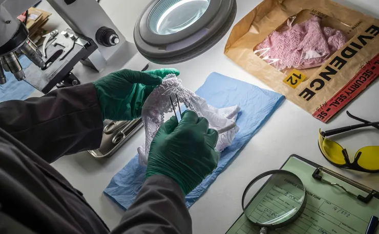 Police scientist inserts rape victim's hair into vial for crime lab DNA research, conceptual image