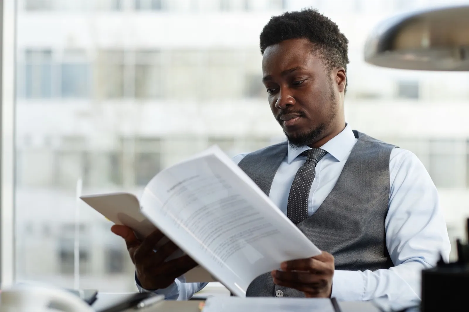 Professional black businessman reading documents at desk in office