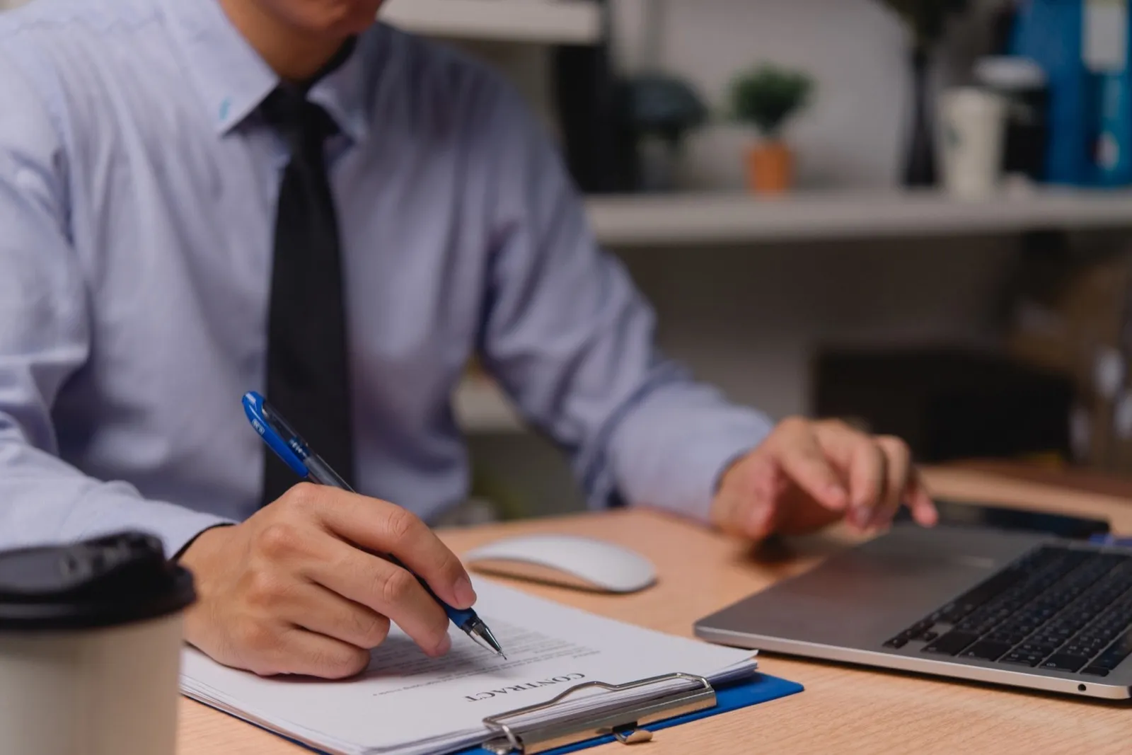 Professional businessman working on contract paperwork with laptop or signing document legal