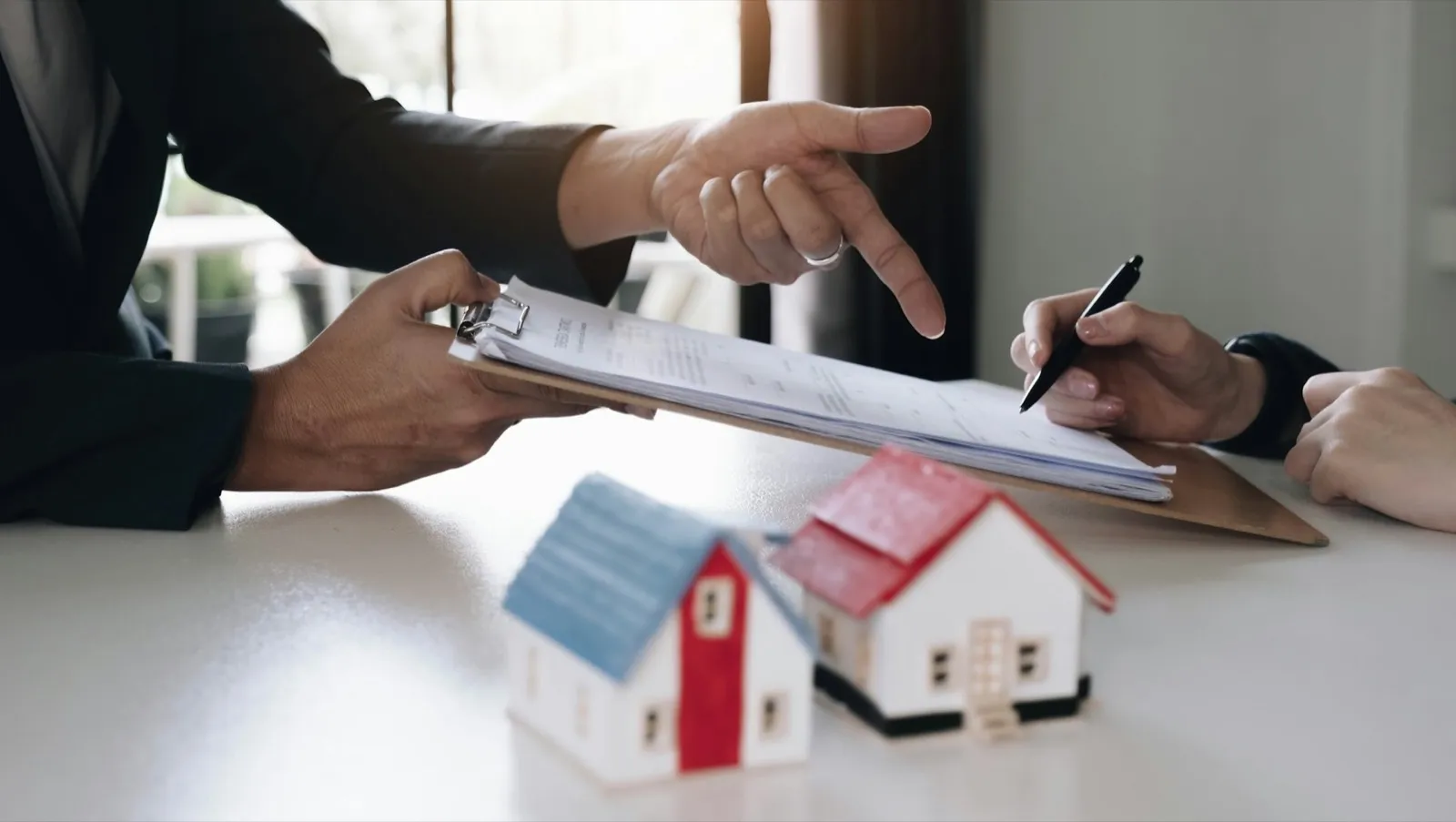 Real estate agent with house model hand putting signing contract,have a contract in place to protect