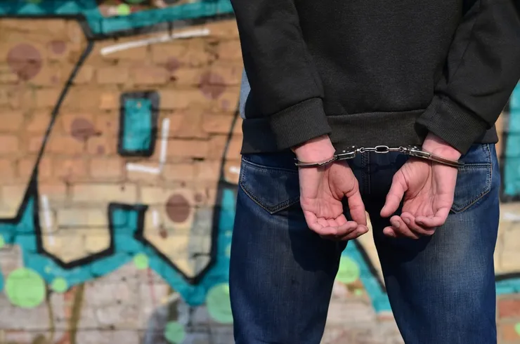 Rear view of the arrested and handcuffed offender against the graffiti background