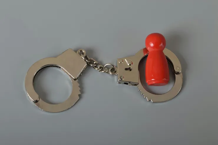 Red wooden people of figure with handcuff locked. Handcuffed convict, law offender and justice