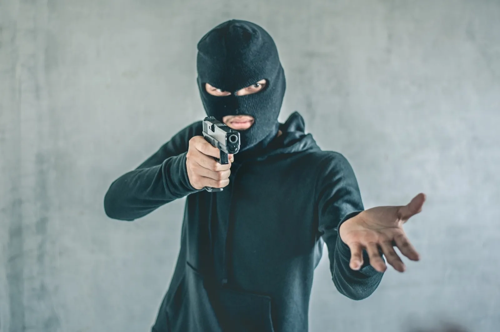 Robber with a gun robbing intimidate.Crime and robbery concept.
