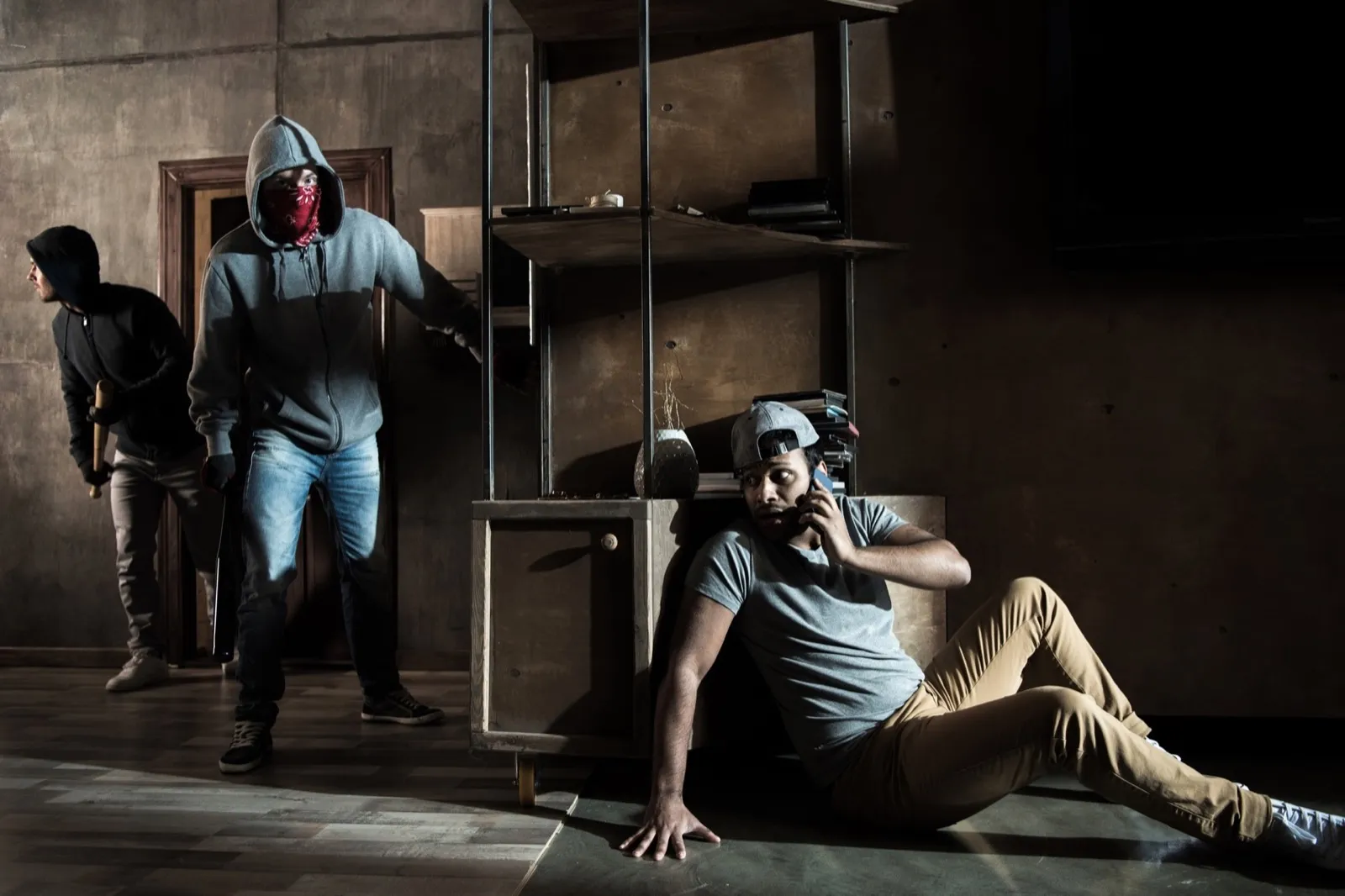 Scared man hiding from burglars breaking indoors, house robbery scene