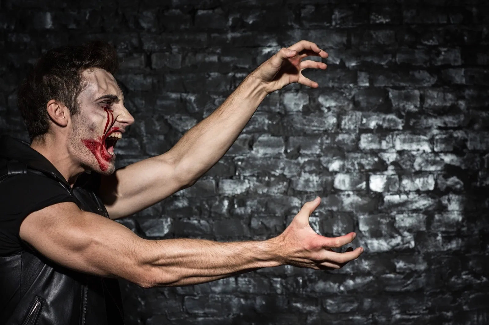 Strong zombie man stretching clawing creepy hands, while attacking someone