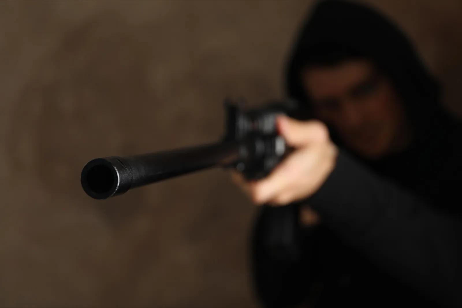 The man in the hood holds gun. Selective focus. Robbery
