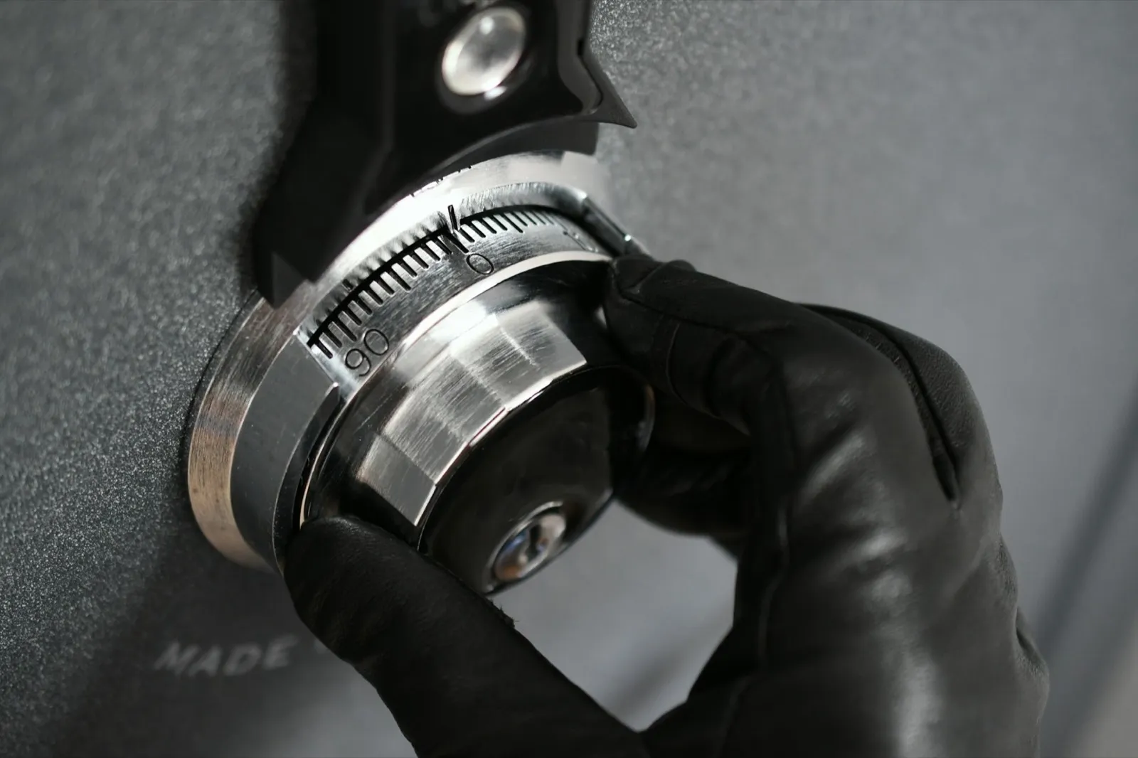 Thief wearing black leather gloves trying to open safe combination lock steal, robbery, crime, theft