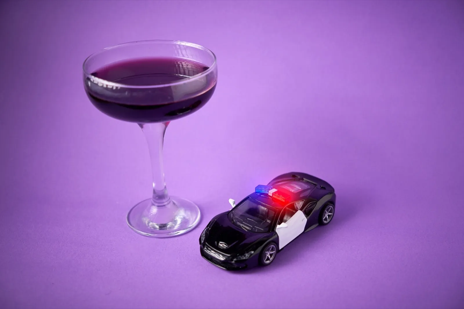 Toy police car with a wine glass. Drunk driving concept and breathalyzer