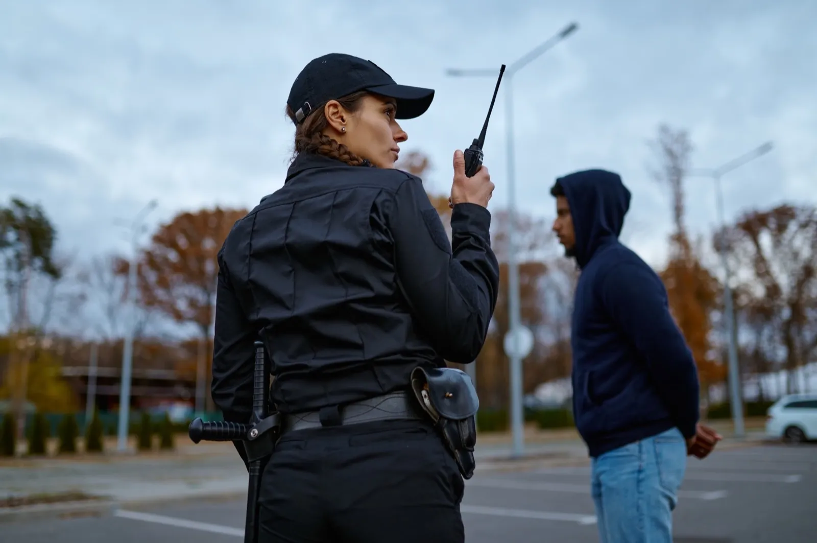 Woman cop using portable radio back view