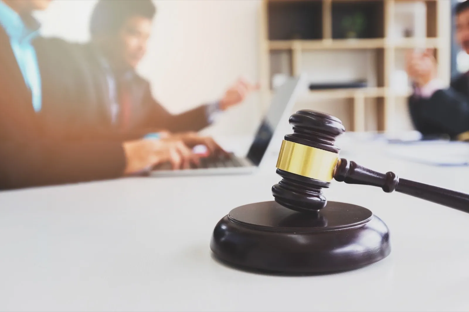 Wooden gavel on table in lawyer’s office. Lawyer having team meeting with the client.