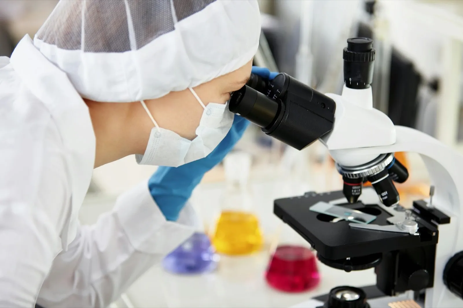 Young woman medical researcher looking through microscop slide in the life science (forensics, micro